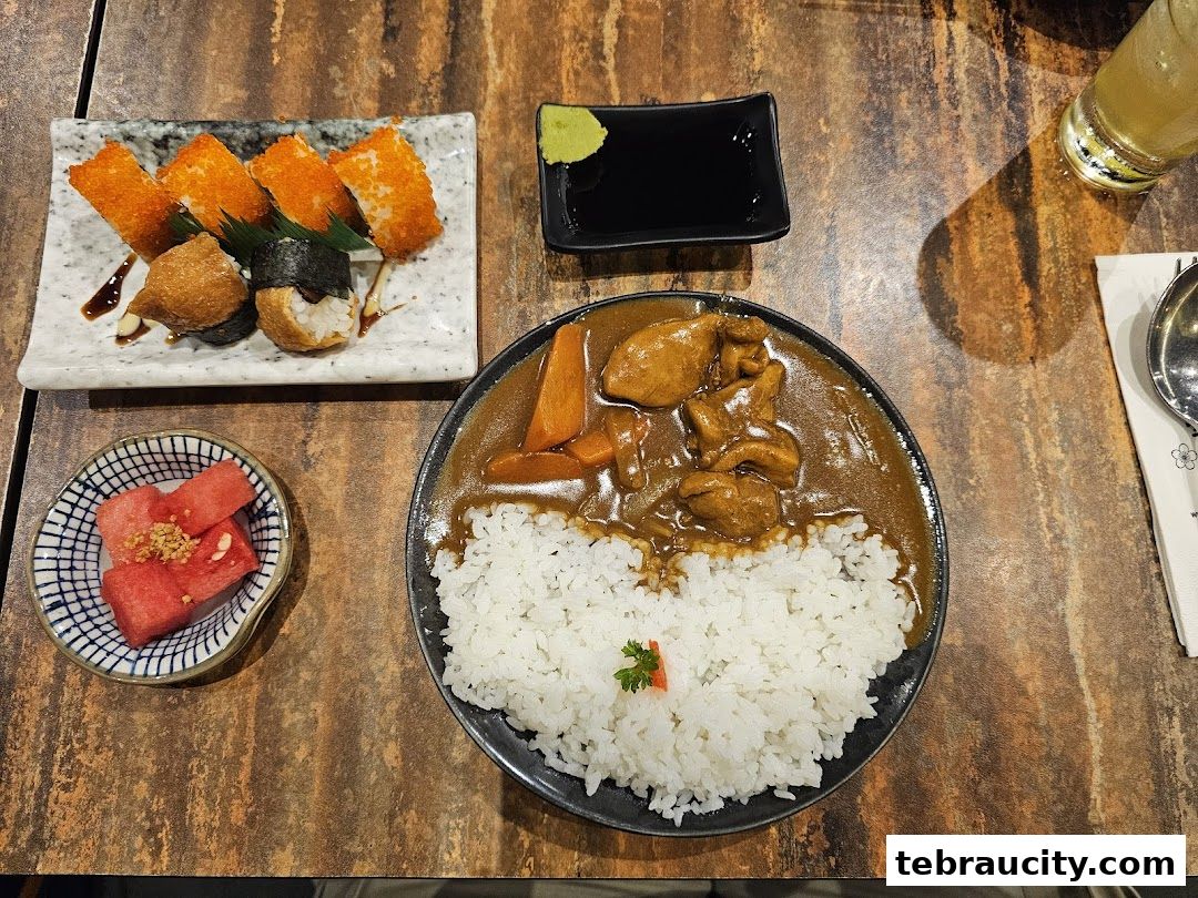 A table at Kinsahi Japanese Restaurant with curry rice, sushi, and watermelon.