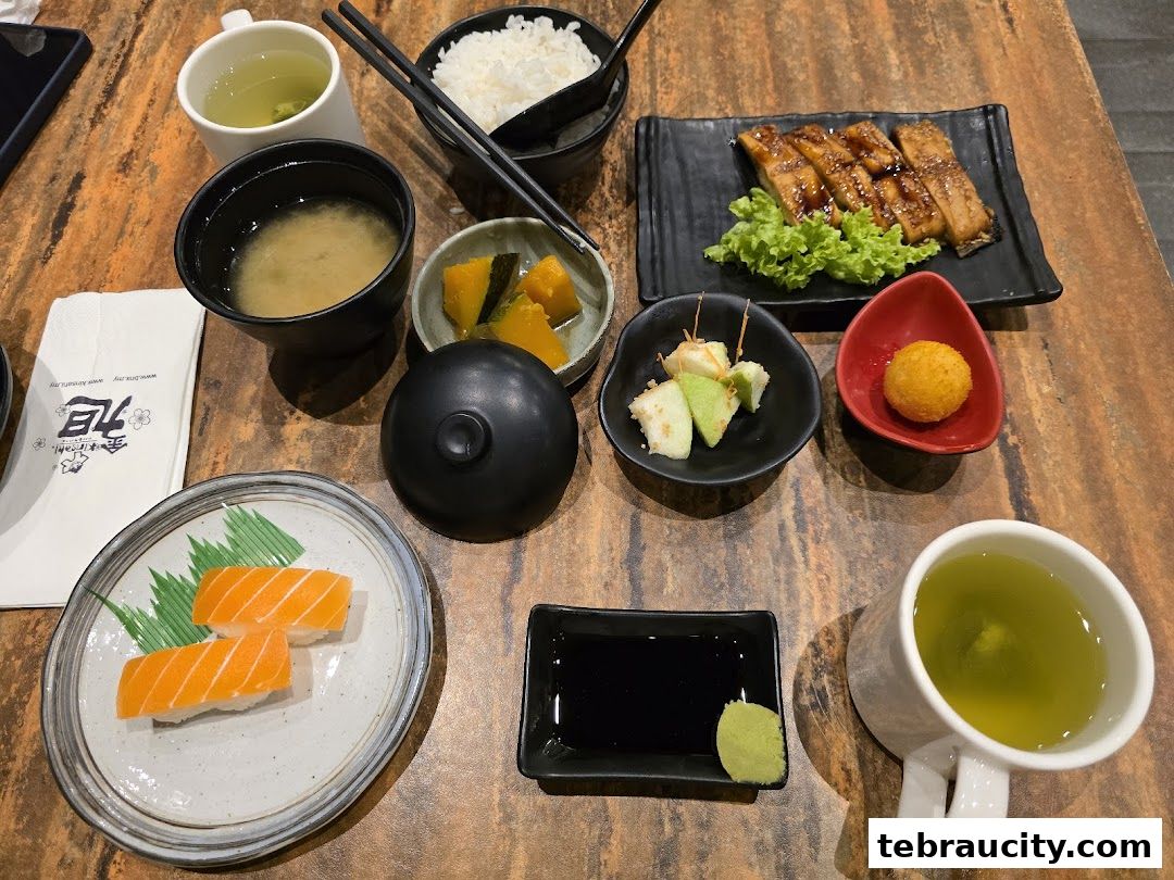 A table setting with Japanese food including sushi, grilled fish, miso soup, rice, and green tea.