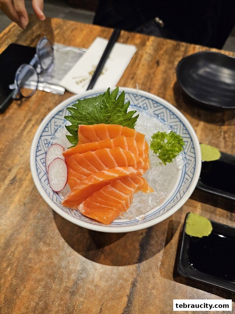 A plate of fresh salmon sashimi served with wasabi and soy sauce on a wooden table.