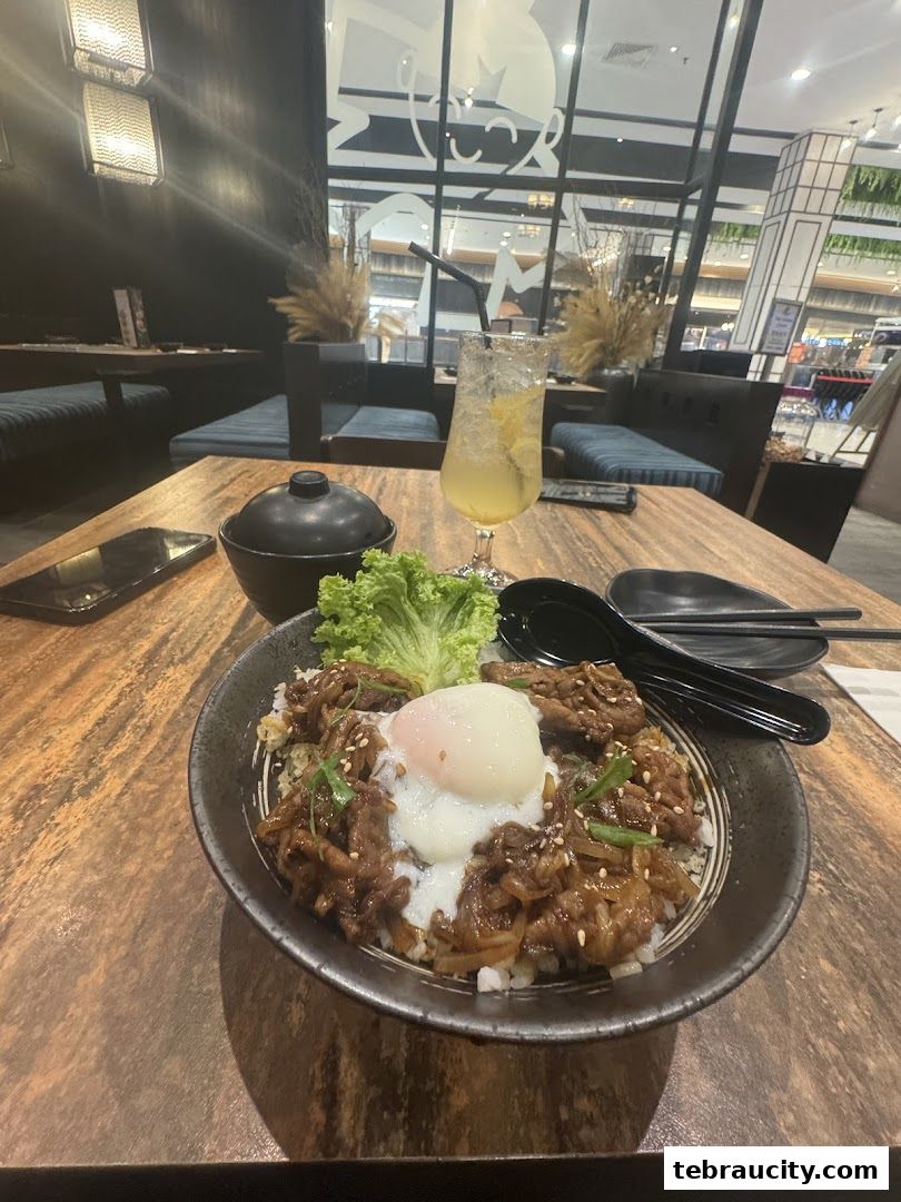 A delicious Japanese rice bowl with beef and a poached egg, served with a refreshing drink.