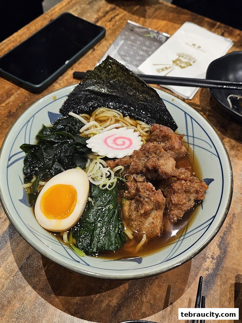 A delicious bowl of ramen with fried chicken, a soft-boiled egg, and seaweed.