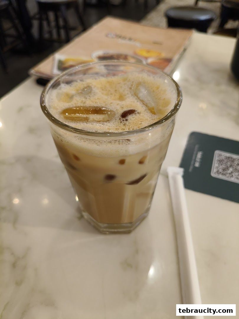 A refreshing iced coffee with milk and ice in a glass on a marble table.
