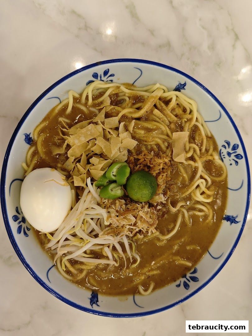 A delicious bowl of noodles with egg, sprouts, lime, and crispy toppings.