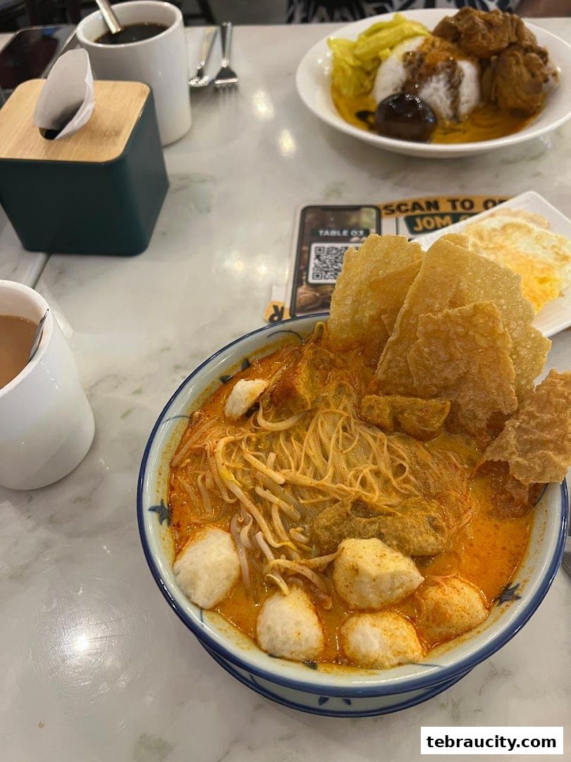 A close-up of a delicious bowl of curry noodles with fish balls and crispy crackers.