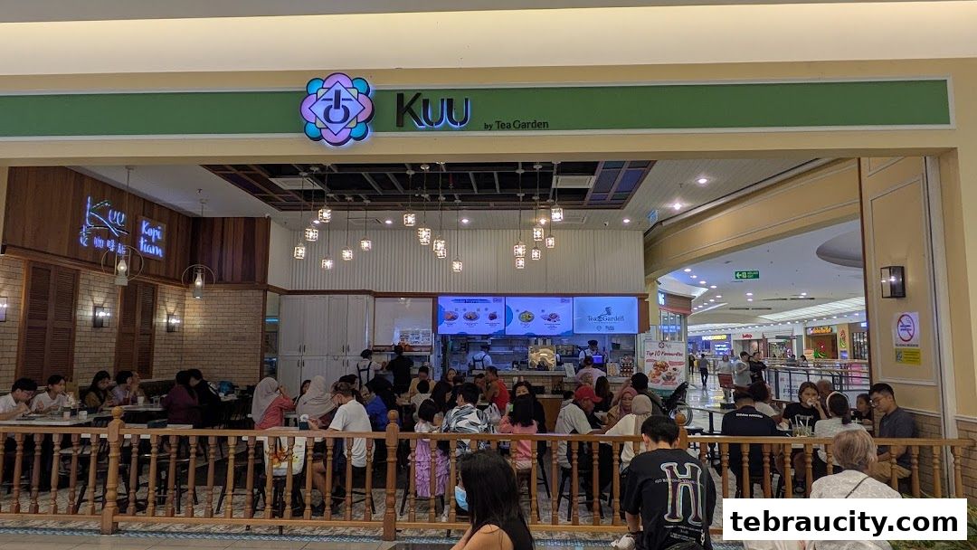 A busy cafe interior with customers seated at tables and a counter with a digital menu.