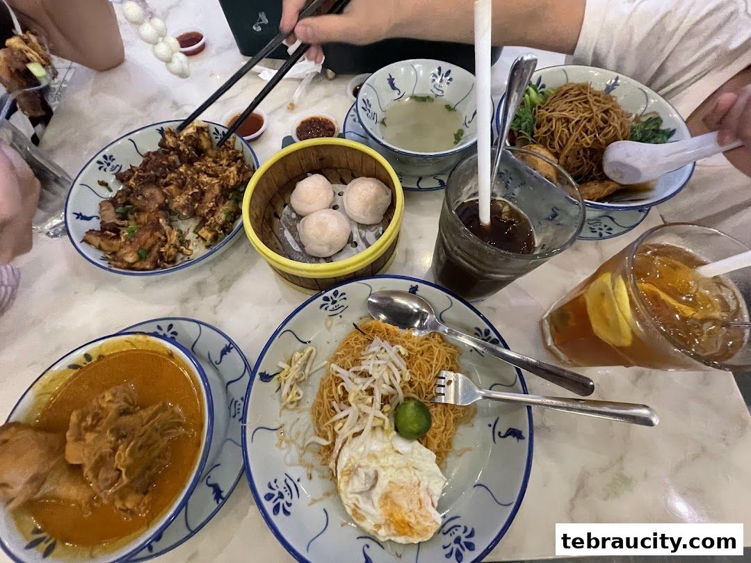 A table filled with various dishes and drinks, including noodles, curry, dim sum, and iced beverages.