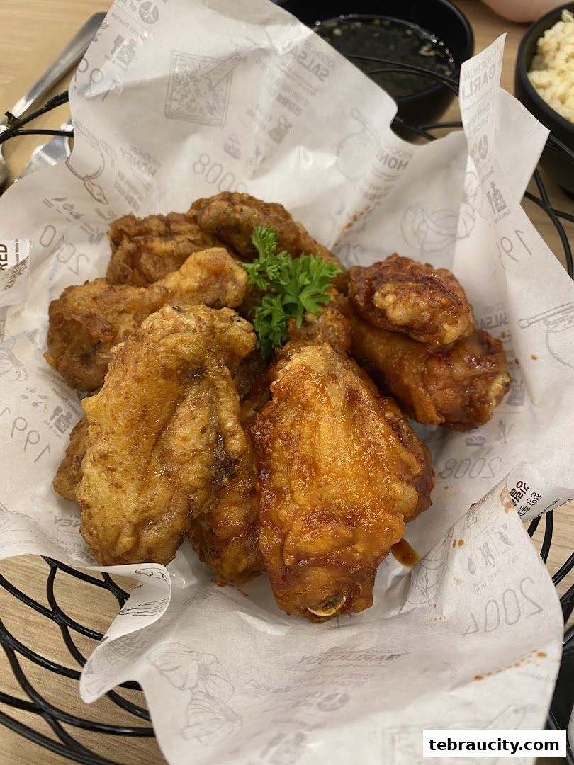 A basket of crispy fried chicken wings, some glazed with sauce, garnished with parsley.
