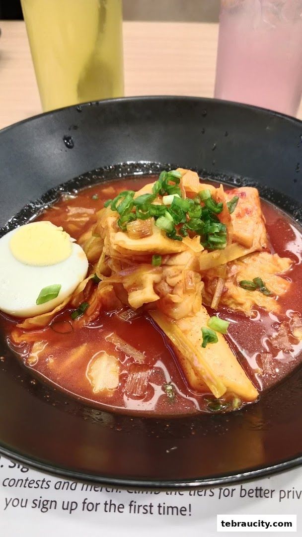 A close-up of a bowl of spicy Korean chicken stew with a boiled egg and green onions.