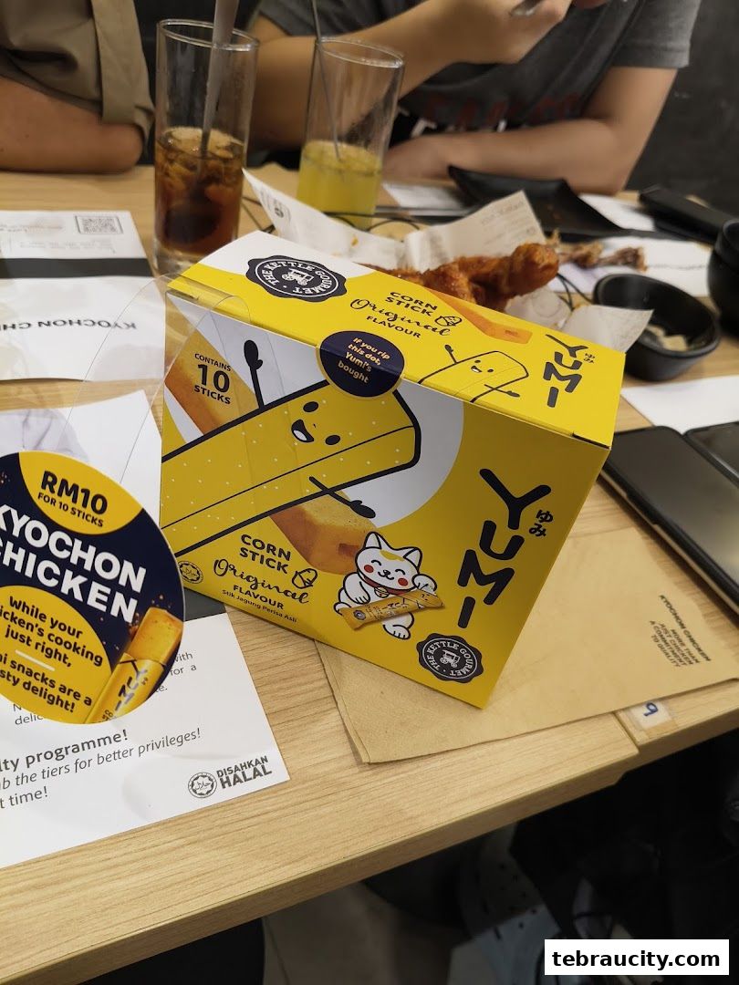 A box of KyoChon Chicken Corn Sticks and fried chicken on a table.