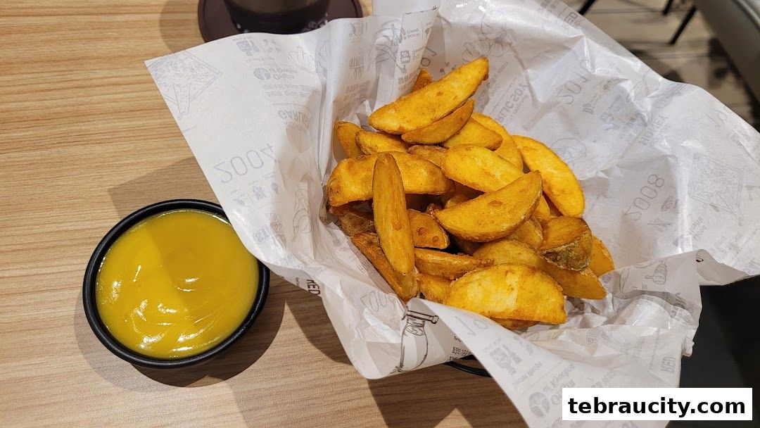 A basket of crispy potato wedges served with a side of dipping sauce.