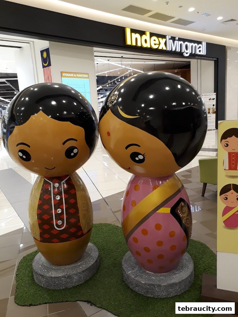 Two large, colorful Kokeshi-style dolls, one male and one female, are displayed in a shopping mall.