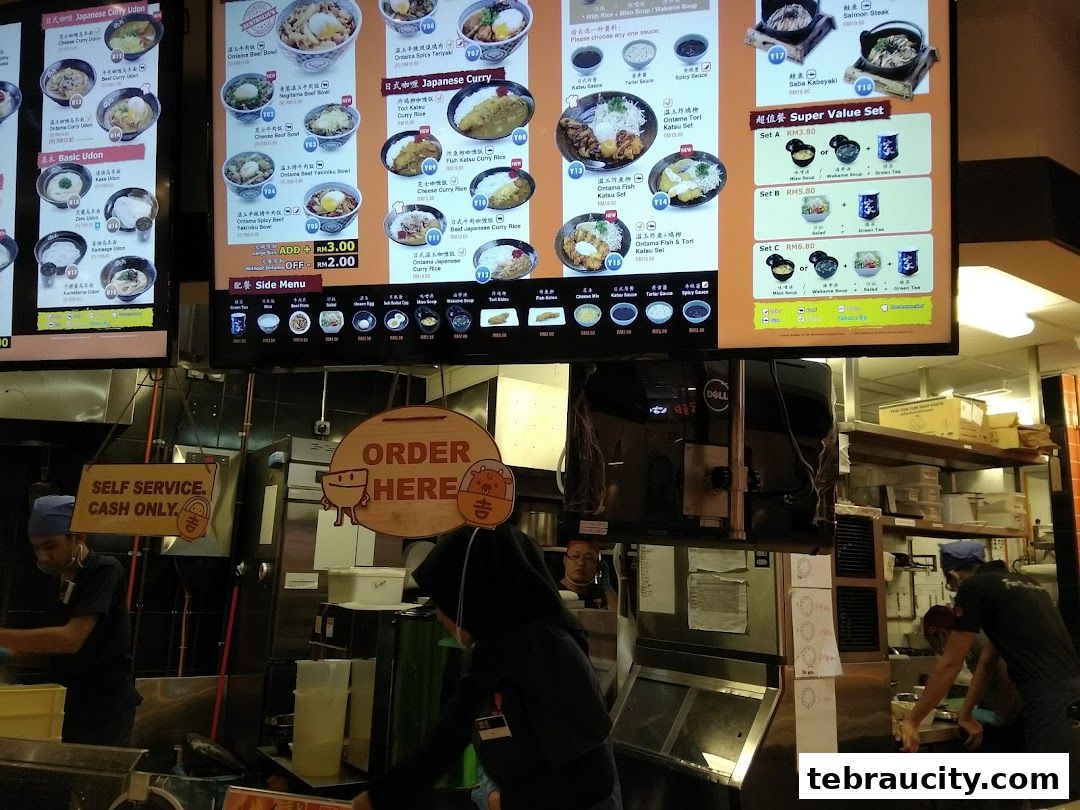 A digital menu board displays various Japanese curry and udon dishes with prices.