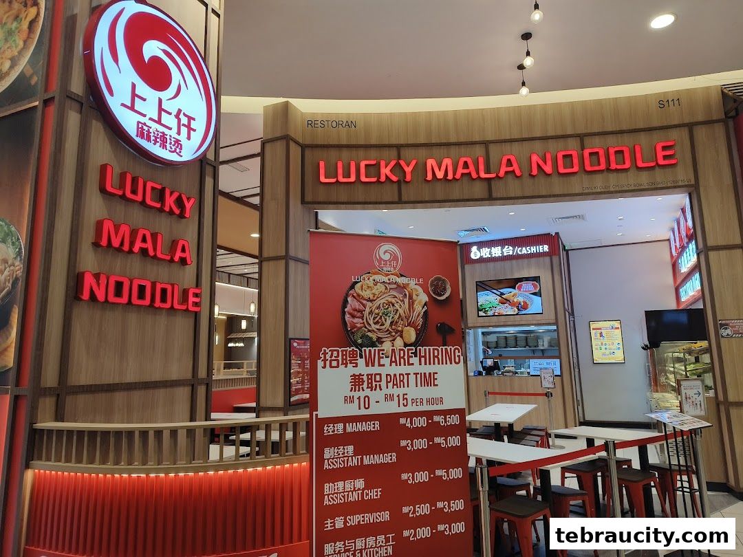 The exterior of a Lucky Mala Noodle restaurant with prominent signage and a hiring advertisement.