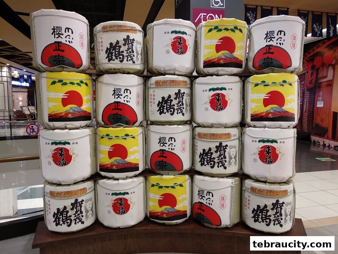 A display of traditional Japanese sake barrels with iconic Mt. Fuji and sun imagery.