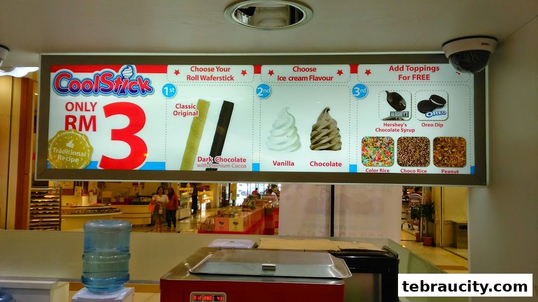 A brightly lit menu board for CoolStick ice cream, showcasing wafer sticks, flavors, and free toppings.
