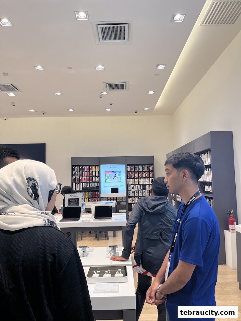 Customers and staff in an Apple Reseller Store, showcasing Apple products and displays.