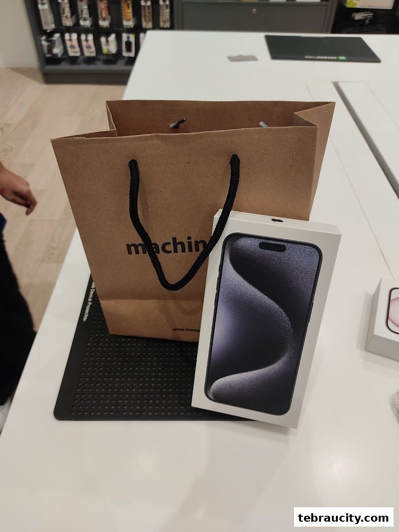 A shopping bag and an iPhone box are displayed on a white counter at an Apple Reseller Store.