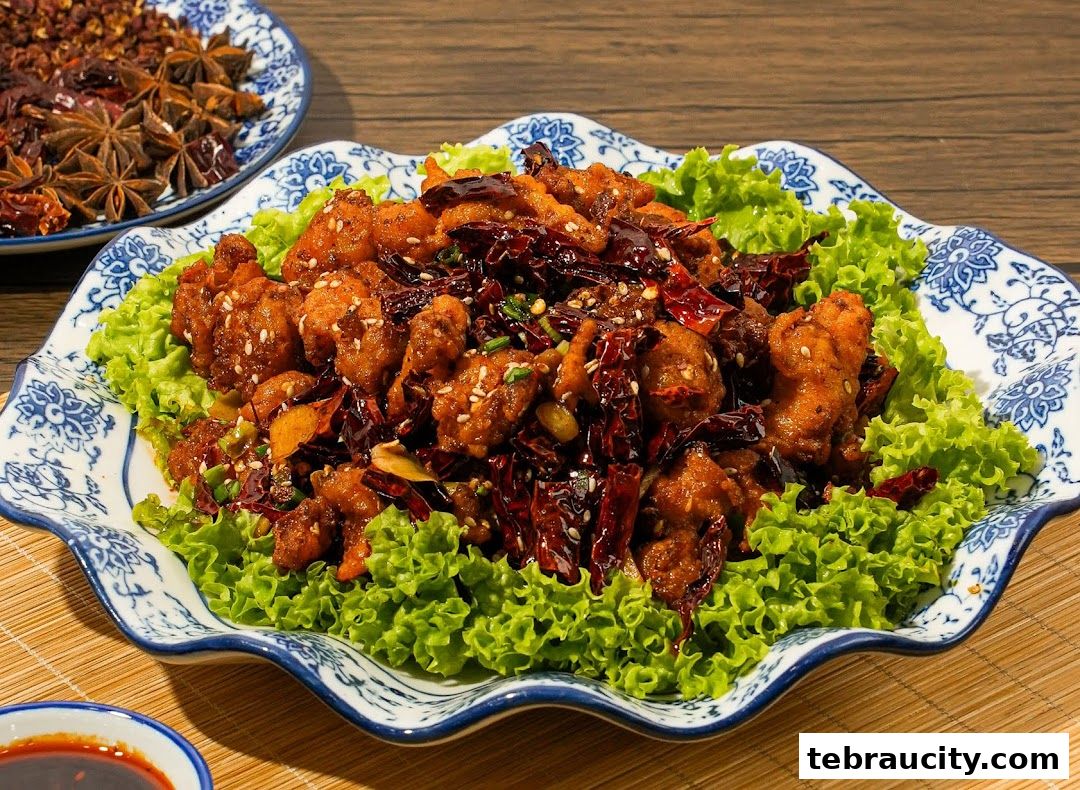 A plate of crispy fried chicken with dried chilies and lettuce, served with a side of star anise.