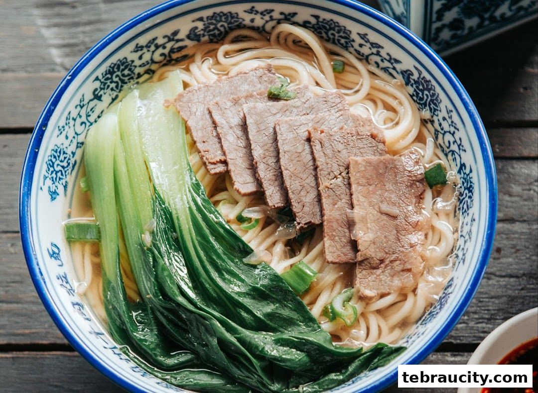 A close-up shot of a steaming bowl of beef noodle soup with bok choy.
