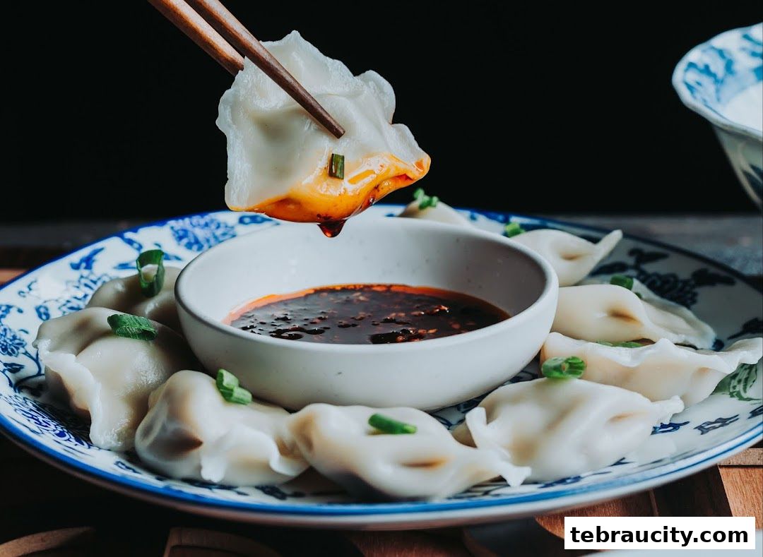 A close-up shot of delicious dumplings being dipped into a savory sauce.