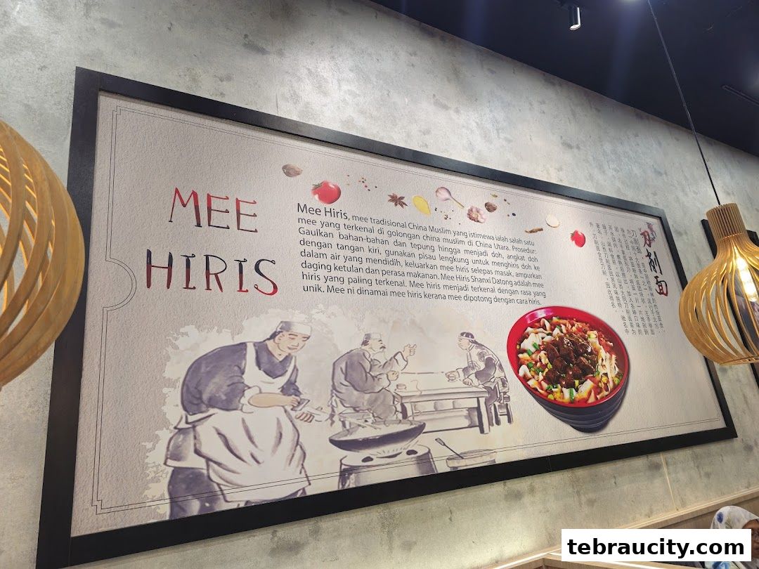 A framed poster inside a restaurant showcasing the history and preparation of Mee Hiris.