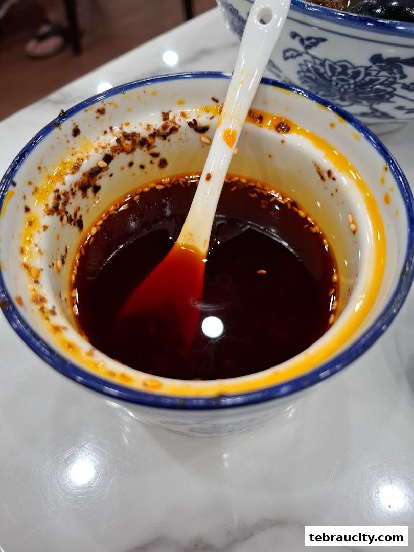 A close-up of a bowl of chili oil with a spoon, likely a condiment for a meal.