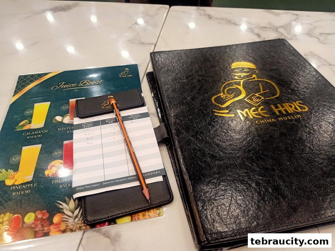 A menu from Mee Hiris China Muslim featuring juice options and a bill holder with a pencil.