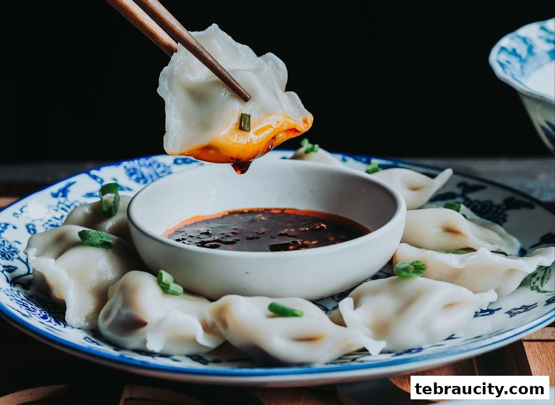 A close-up shot of delicious dumplings being dipped into a spicy chili oil sauce.