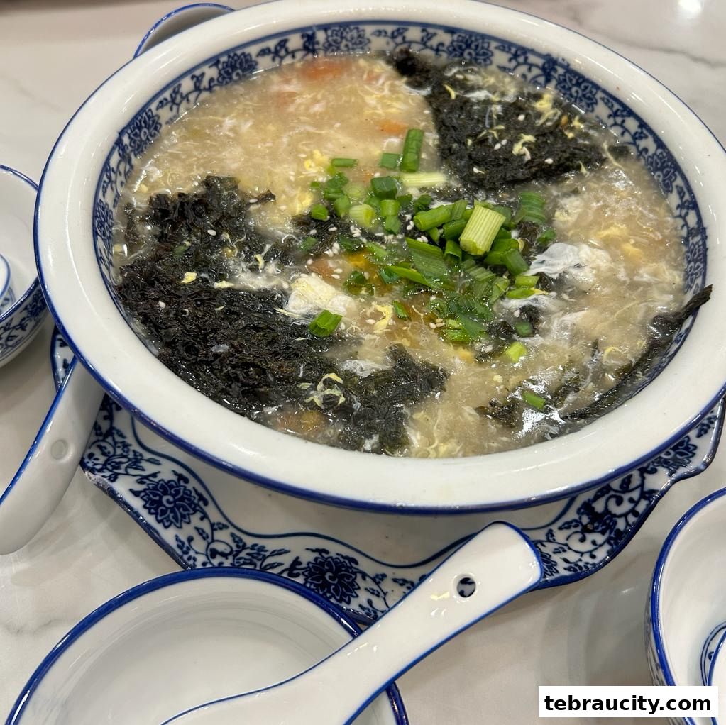 A close-up of a steaming bowl of soup with seaweed, egg, and green onions.