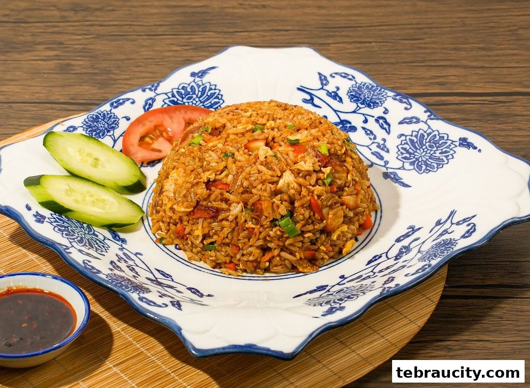 A plate of fried rice with cucumber and tomato slices, served with dipping sauce.