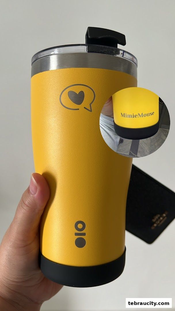 A hand holds a bright yellow insulated tumbler with a heart and speech bubble logo.