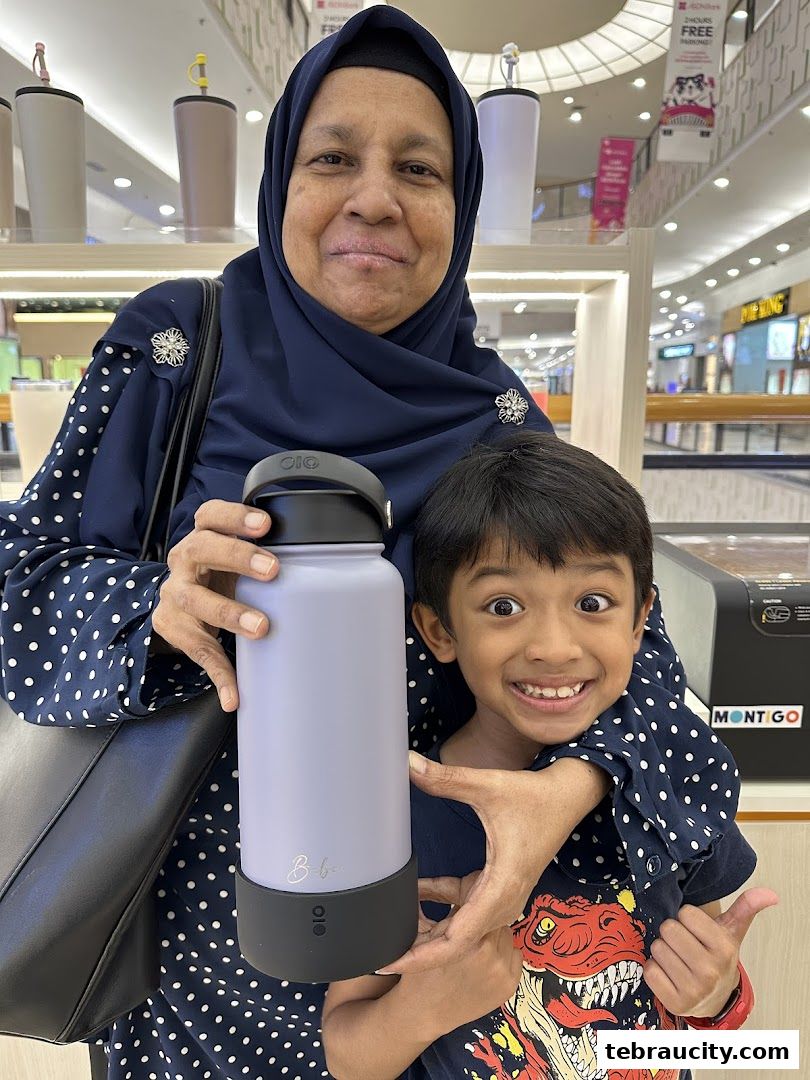 A woman and a child happily pose with a Montigo water bottle in a store.
