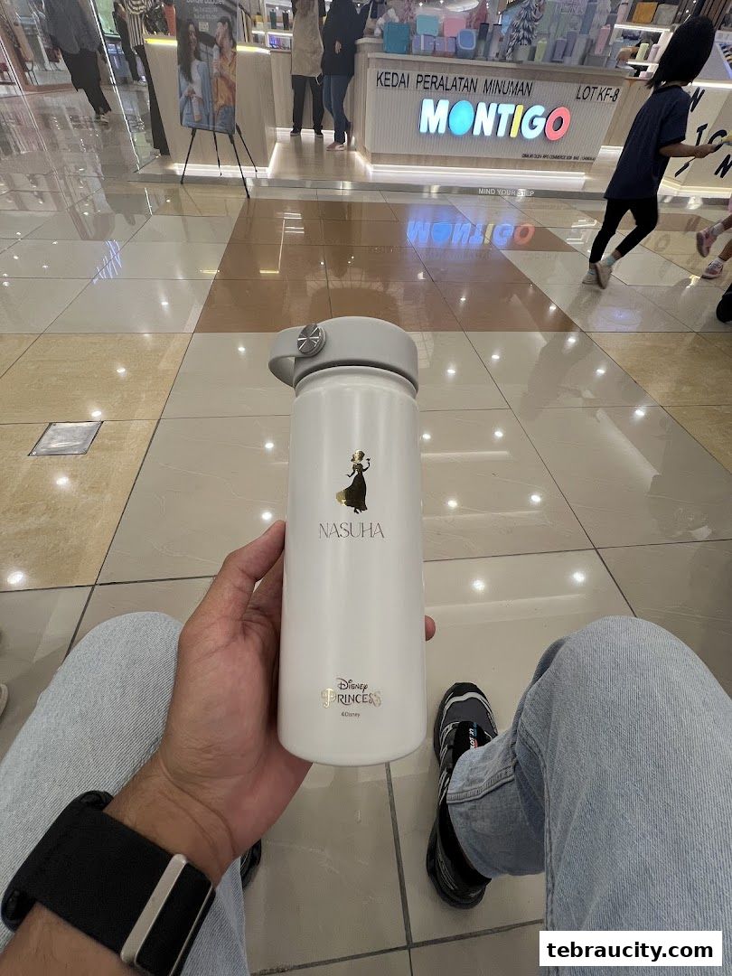 A person holds a white Montigo water bottle with a Disney Princess design.