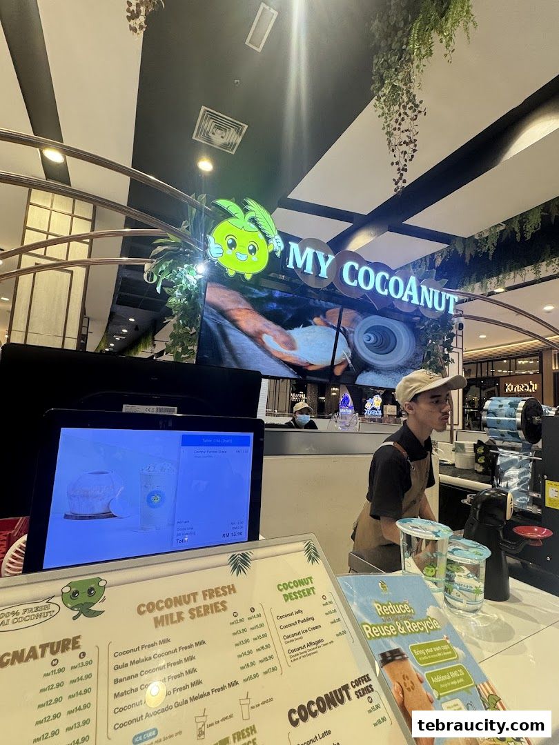 A counter at My Cocoanut Aeon Tebrau City with a menu and a staff member.