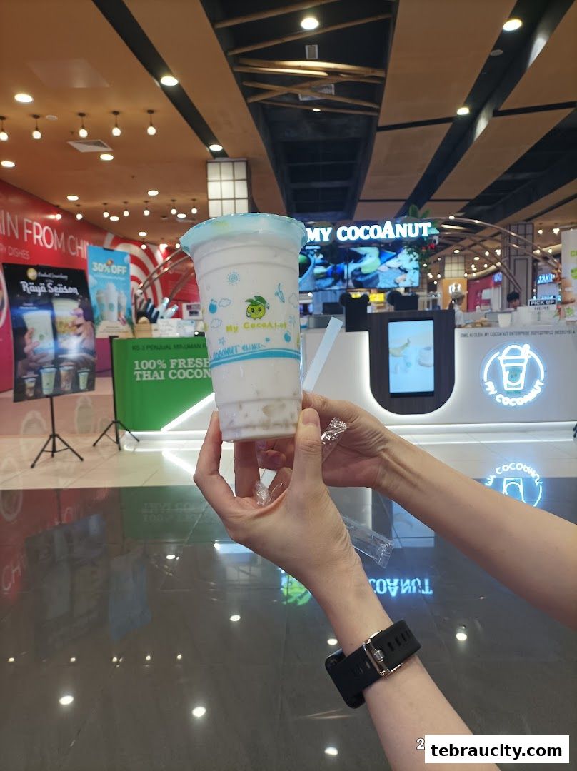 A person holds a coconut drink in front of the My Cocoanut shop.