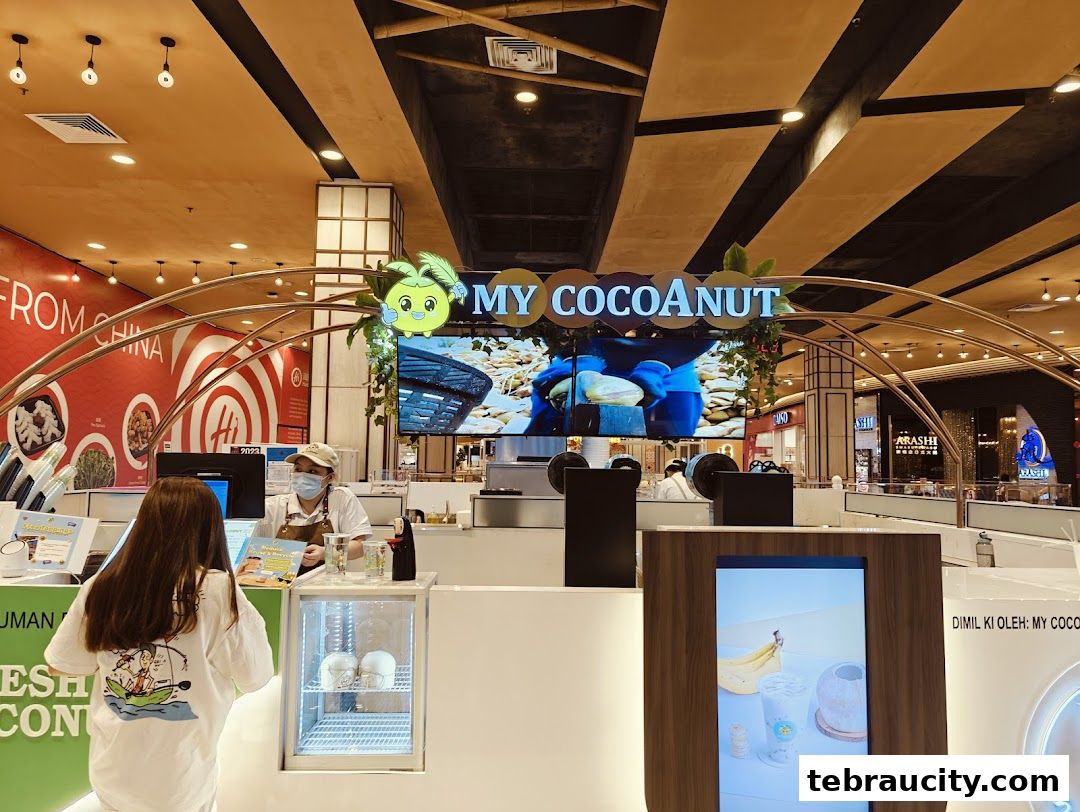 A customer orders at a brightly lit My Cocoanut stall in a shopping mall.