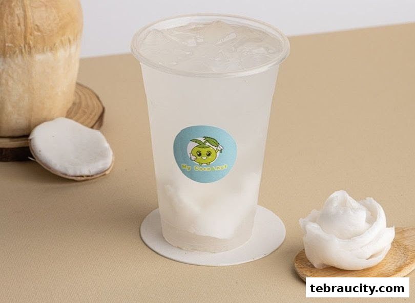 A refreshing coconut drink with fresh coconut pieces and a whole coconut.