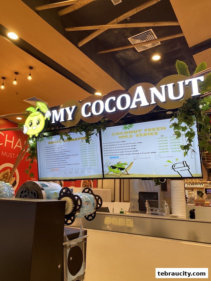 A digital menu board displaying various coconut shakes and fresh milk drinks at My Cocoanut.