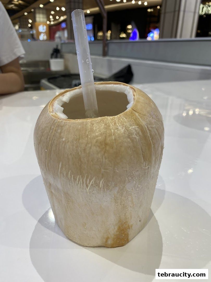 A refreshing whole coconut with a straw, ready to be enjoyed.