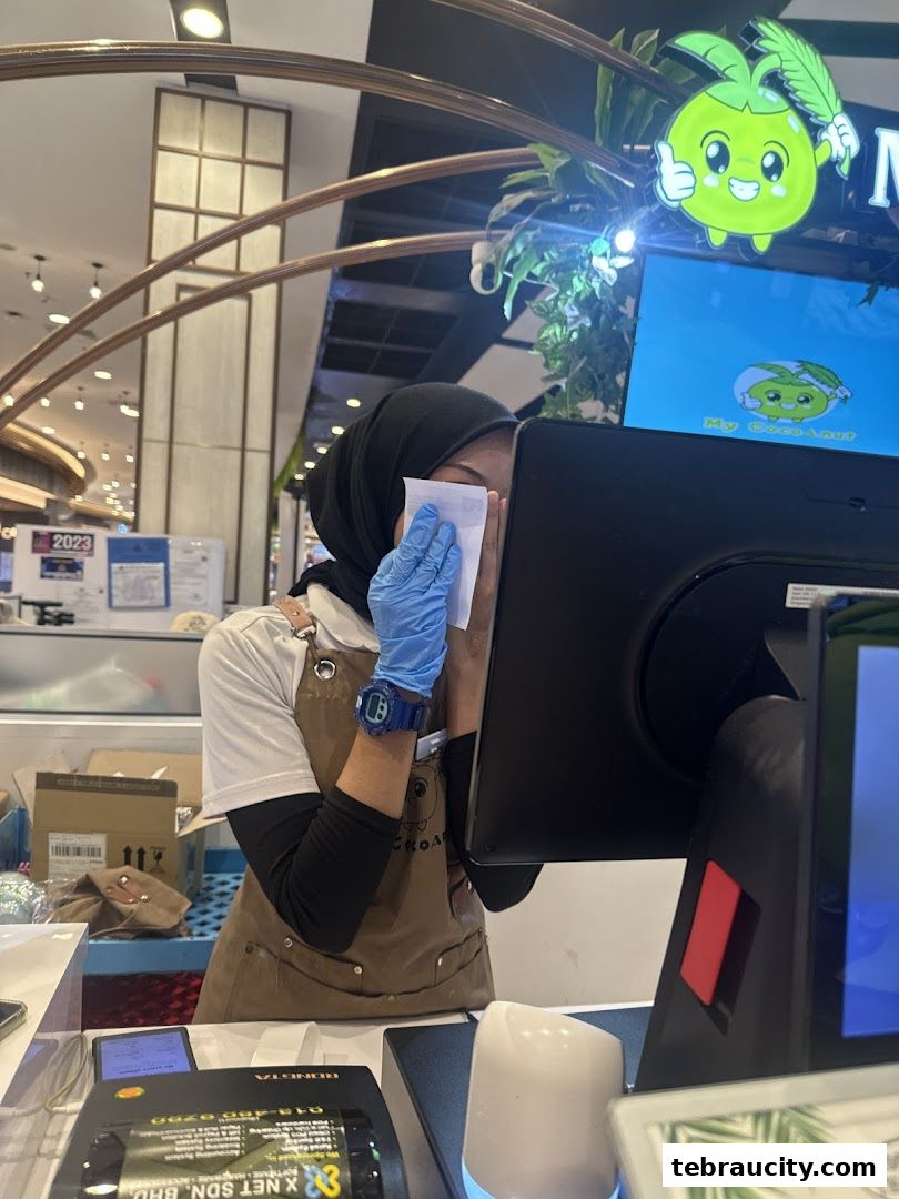 A staff member at My Cocoanut wipes the screen of a computer with a tissue.