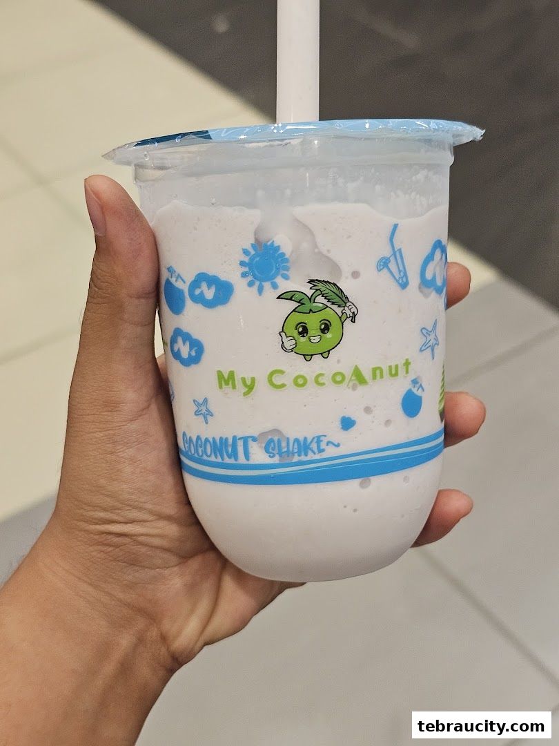 A hand holds a refreshing coconut shake from My Cocoanut Aeon Tebrau City.