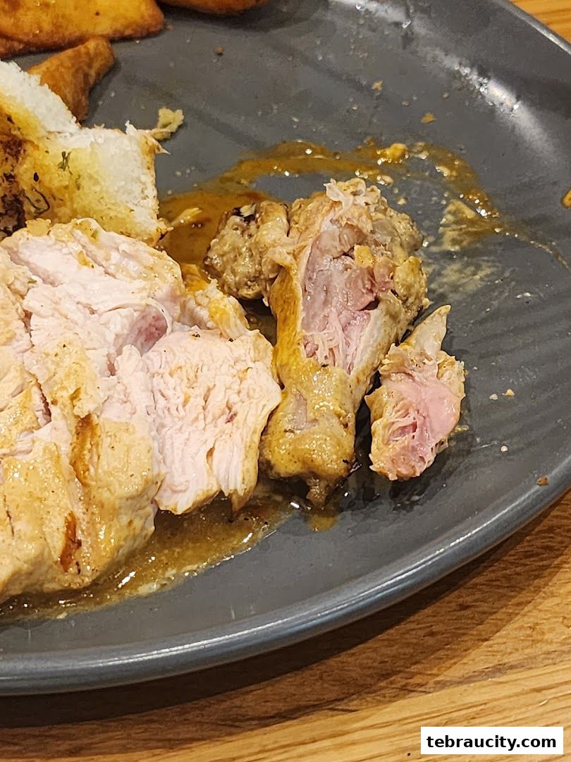 A close-up of a plate of peri-peri chicken with bread and sauce.