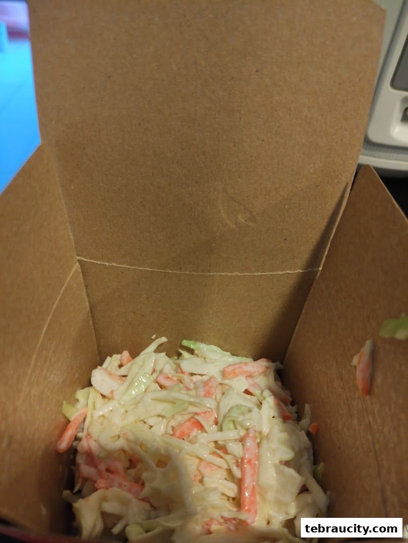A close-up view of coleslaw in a brown cardboard container.
