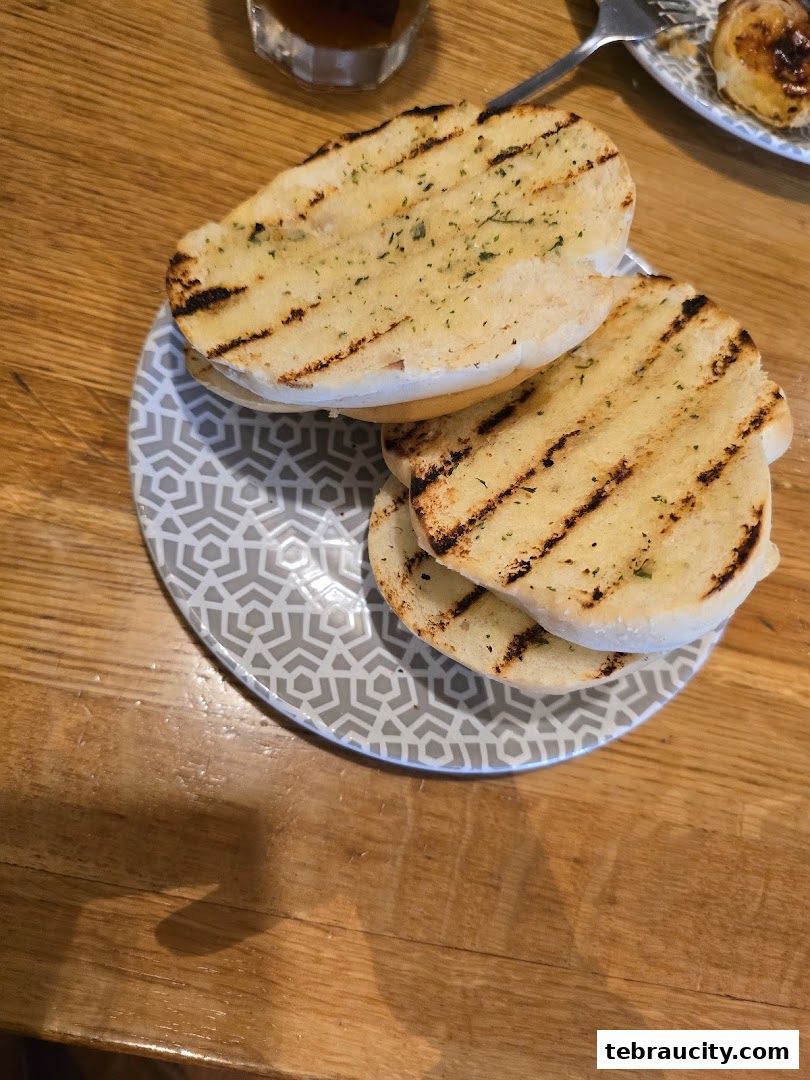 A plate of grilled garlic bread with herbs on a wooden table.