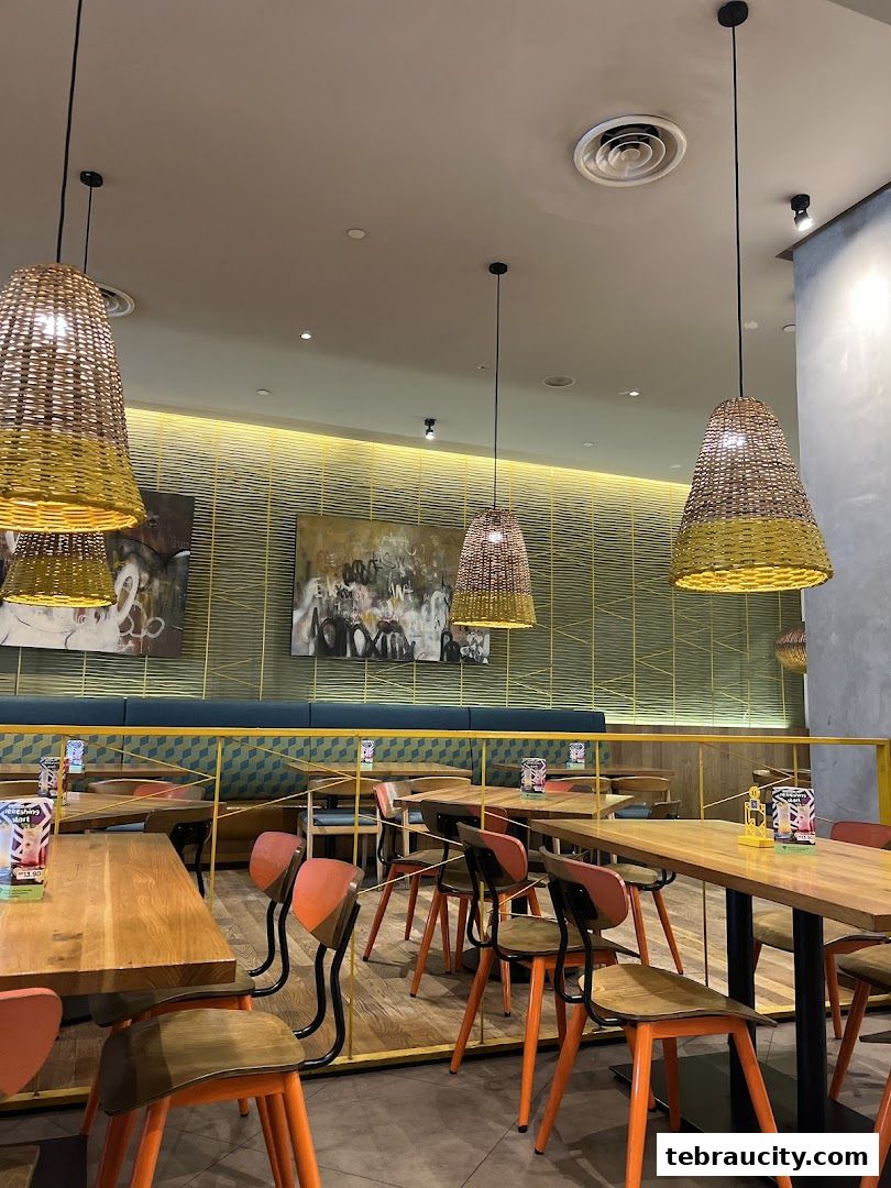 Interior view of a Nandos restaurant with wooden tables, chairs, and unique woven lamps.