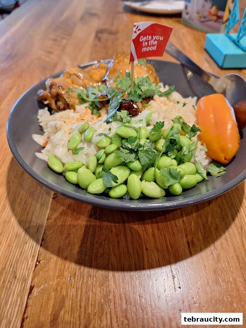 A close-up of a delicious Nando's meal with chicken, rice, edamame, and a signature flag.