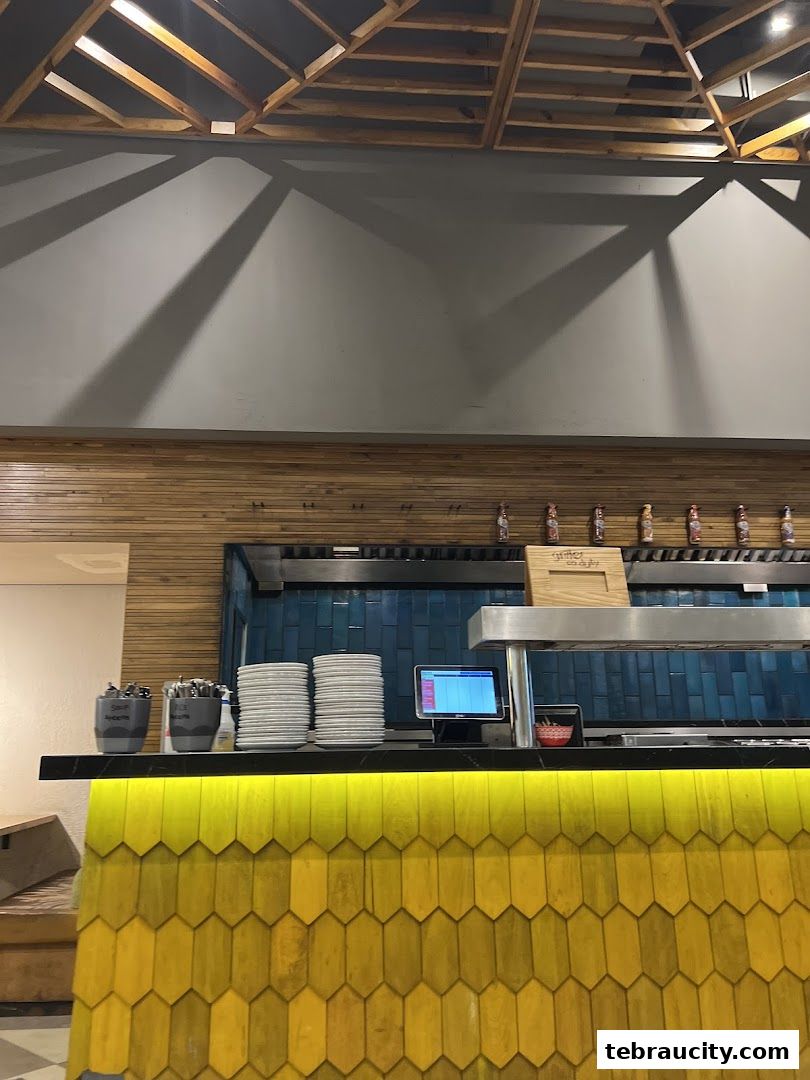 Interior view of a restaurant counter with stacks of plates and a POS system.
