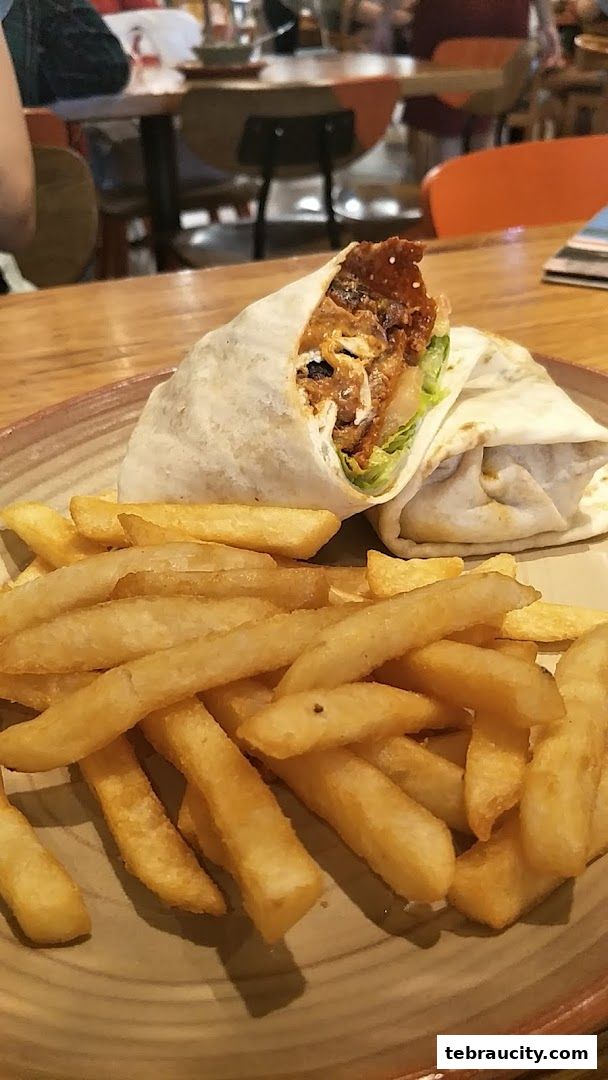 A delicious wrap with fries served on a plate at Nandos.
