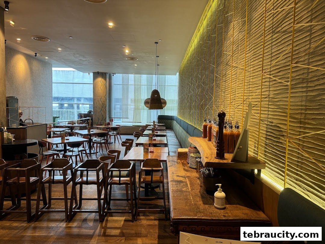 Interior view of a Nandos restaurant with tables, chairs, and a decorative wall.