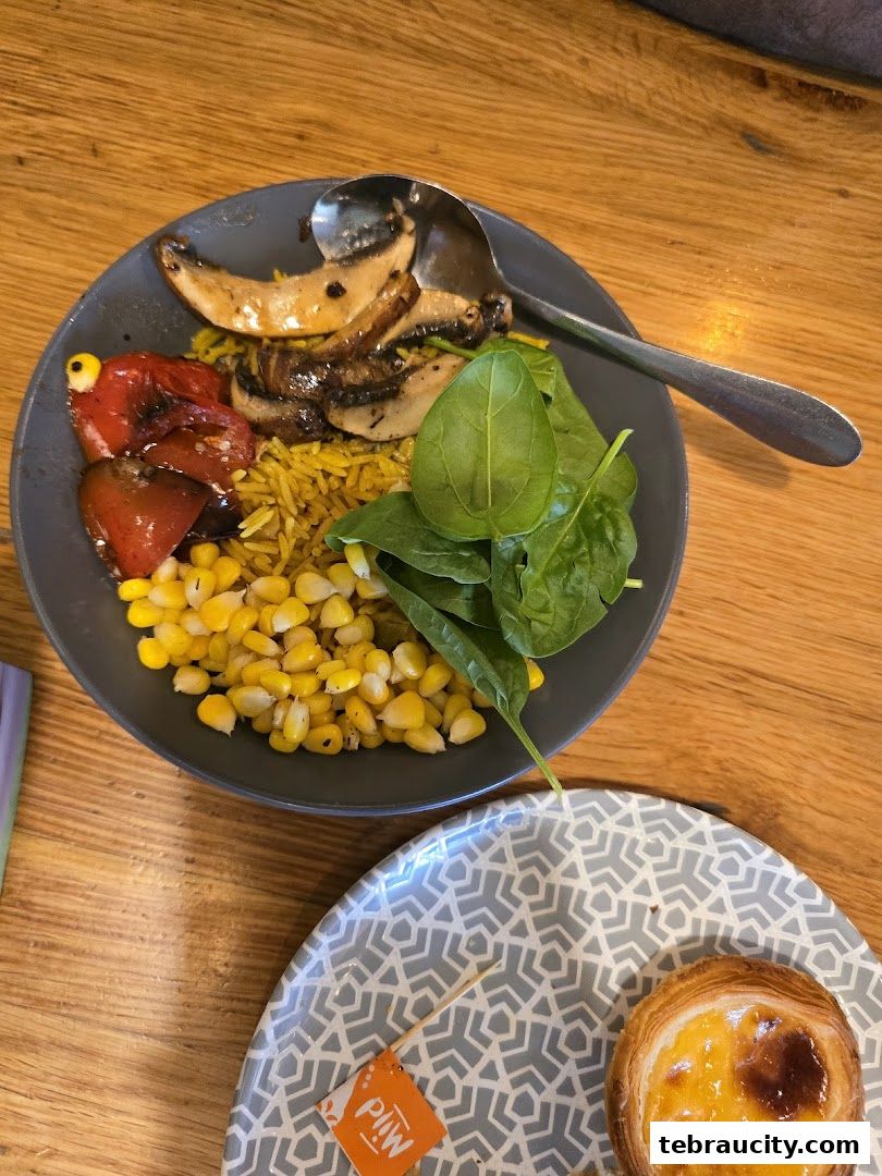 A plate of rice with corn, mushrooms, peppers, and spinach, next to a pastry.